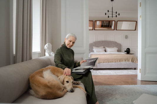 Older person sitting happily with a dog and cat